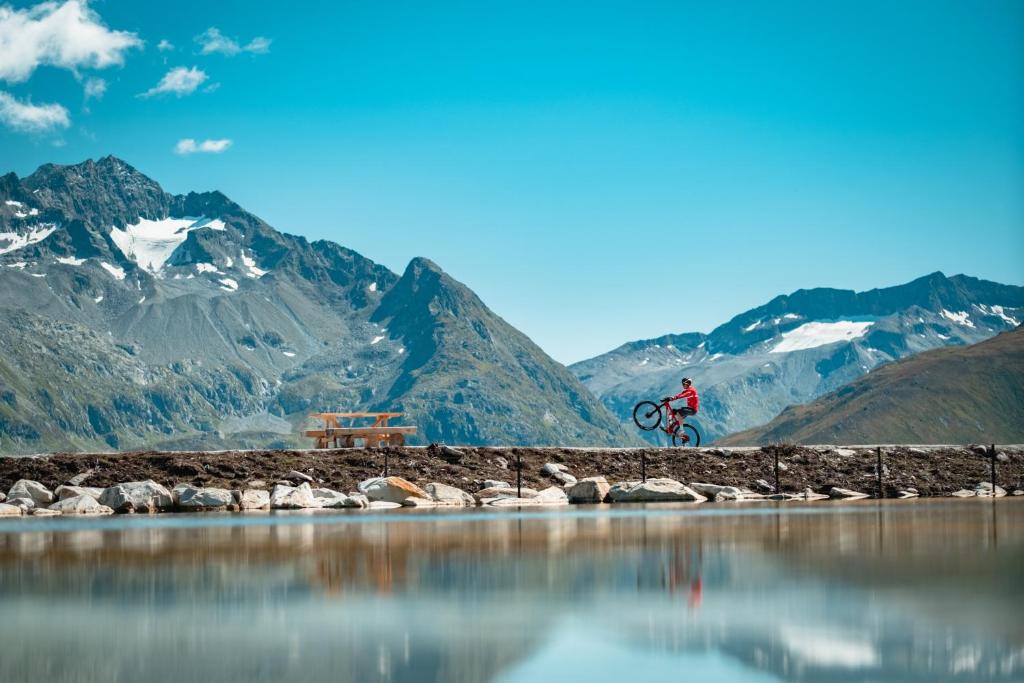 a person riding a bike next to a body of water at Catrina Lodge in Disentis