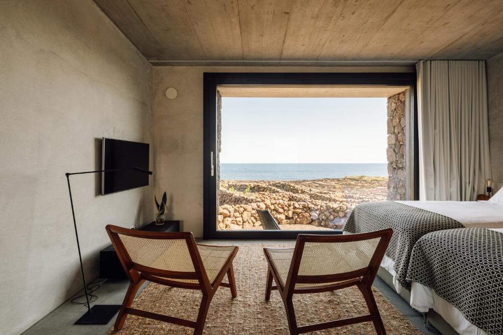 a bedroom with two chairs and a view of the ocean at Azores Wine Company in Cais do Mourato
