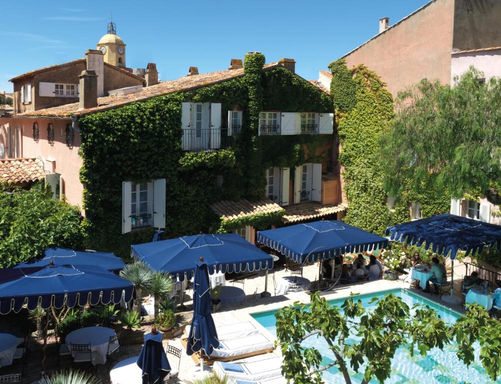 a patio with umbrellas and chairs in front of a house at Hôtel Le Yaca in Saint-Tropez