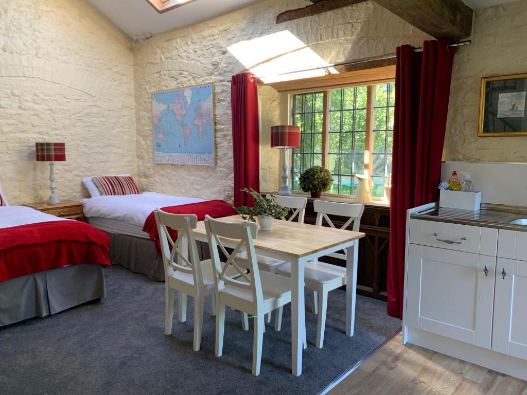 una habitación con mesa y sillas y un dormitorio en Garden Barn, en Farthinghoe