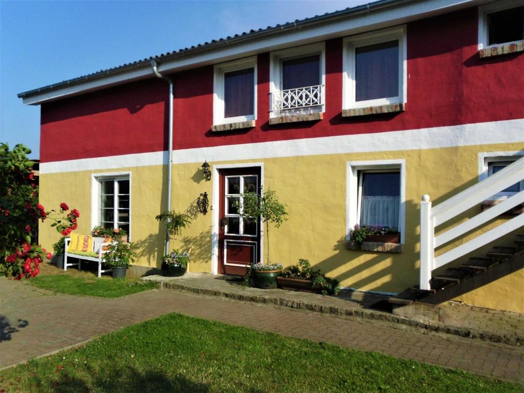 uma casa vermelha amarela e branca com uma varanda em Rosenhof Ferienwohnungen em Mölln-Medow