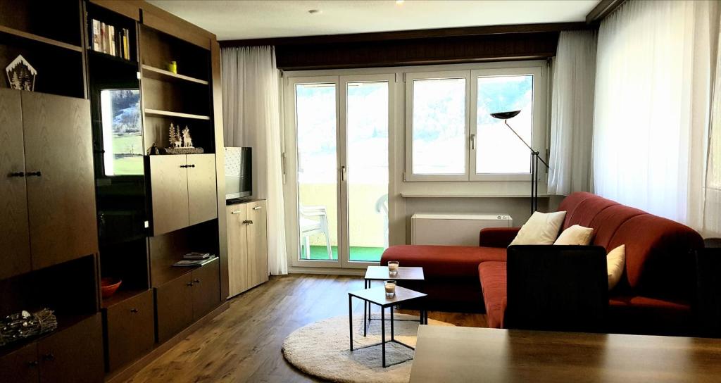 un soggiorno con divano rosso e una grande finestra di Lorée 201 a Leukerbad
