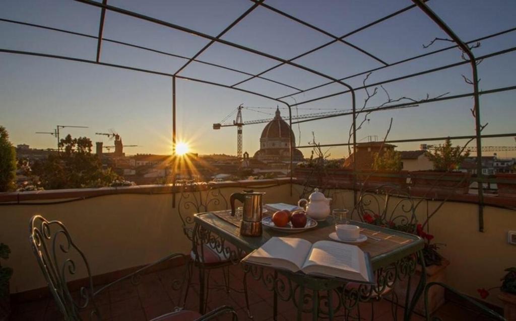 a table and chairs on a balcony with the sunset at Signorelli Halldis Apartment in Florence