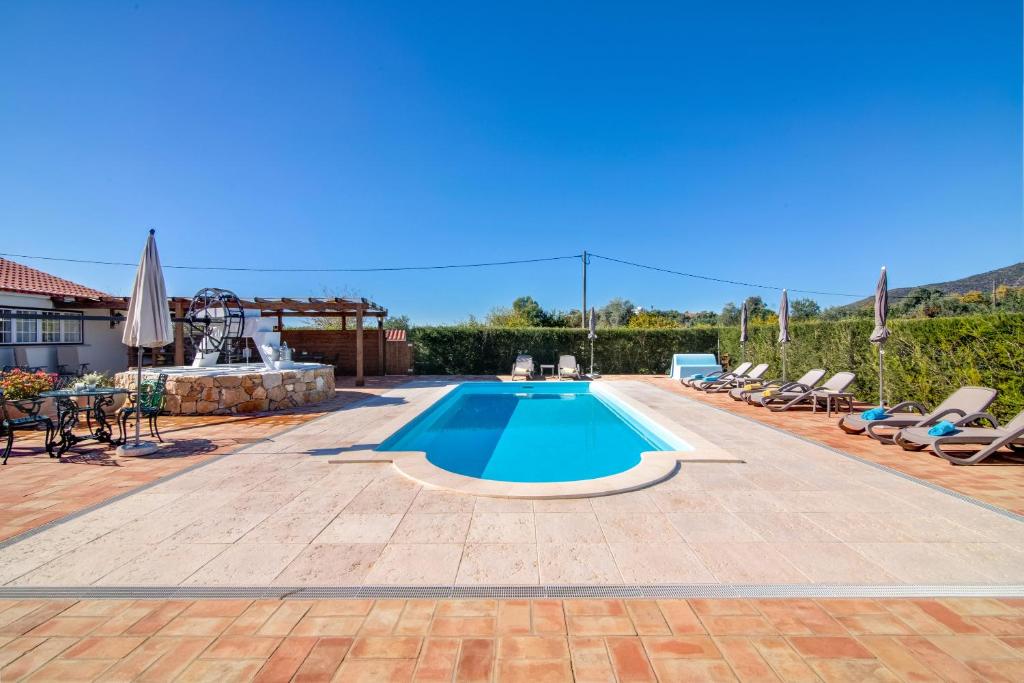 uma piscina num quintal com cadeiras e uma mesa em Villa Oliva Al em Moncarapacho