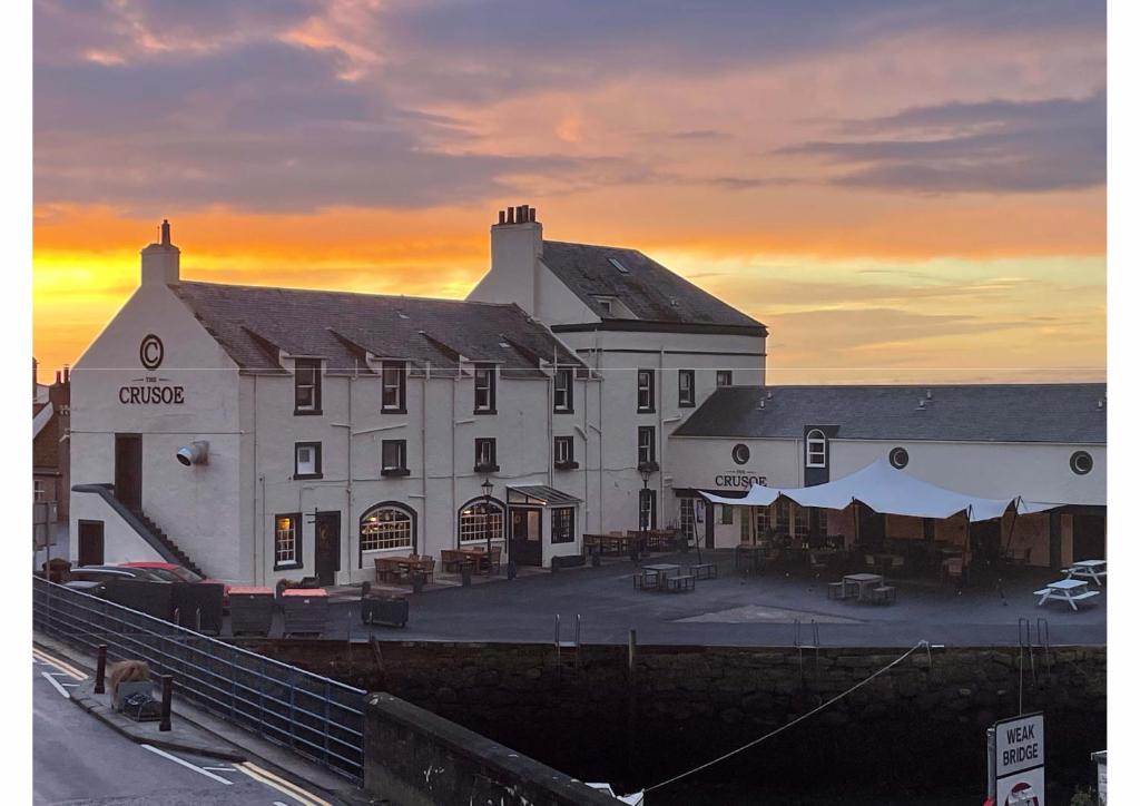 un grande edificio bianco con un tramonto sullo sfondo di The Crusoe a Leven-Fife