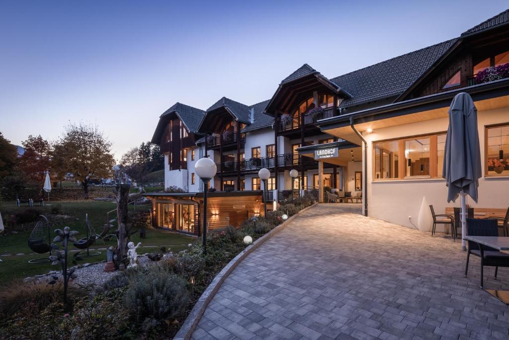 un edificio con un patio con una mesa y una sombrilla en Naturhotel Landhof Irschen, en Irschen