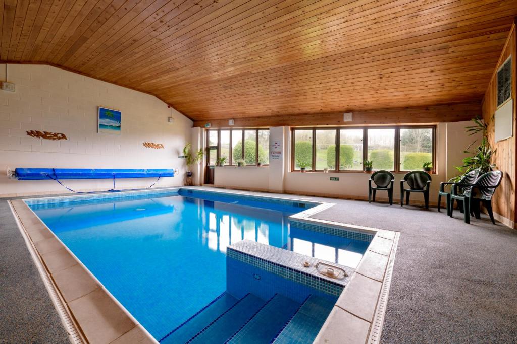 a swimming pool in a house with a wooden ceiling at Luccombe Farm Holiday Cottages in Milton Abbas