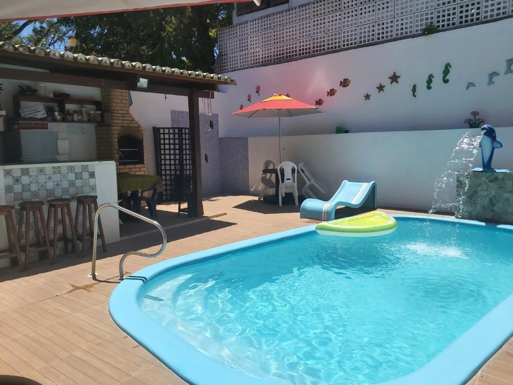 una piscina con sombrilla, mesa y sillas en Residencial Fran Chiattone, en Natal