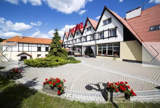 een groot gebouw met rode bloemen ervoor bij Hotel Górecki in Lidzbark Warmiński