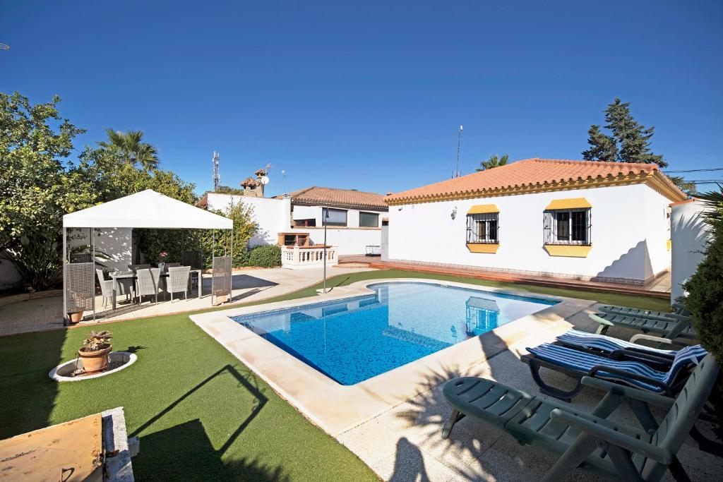 un patio trasero con piscina y una casa en Casa Adela, en Chiclana de la Frontera