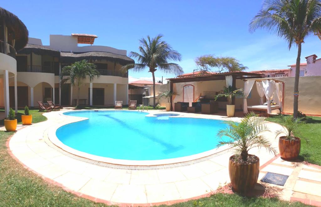 uma piscina em frente a uma casa com palmeiras em Villa Serena em Canoa Quebrada