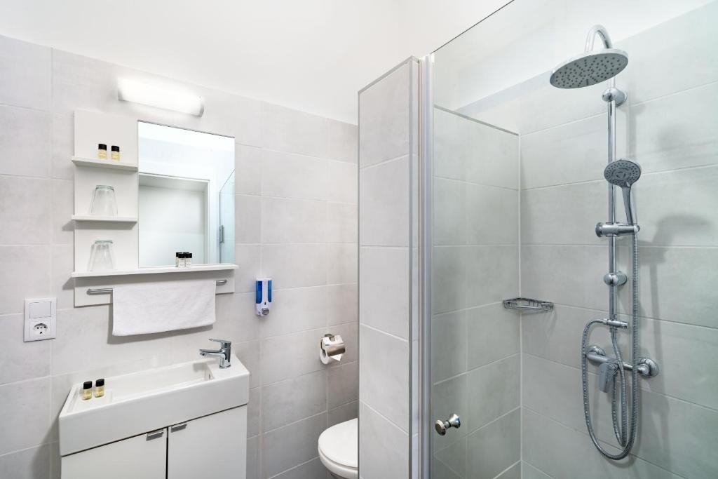 a bathroom with a shower and a toilet and a sink at RES City Residence Hotel Budapest in Budapest