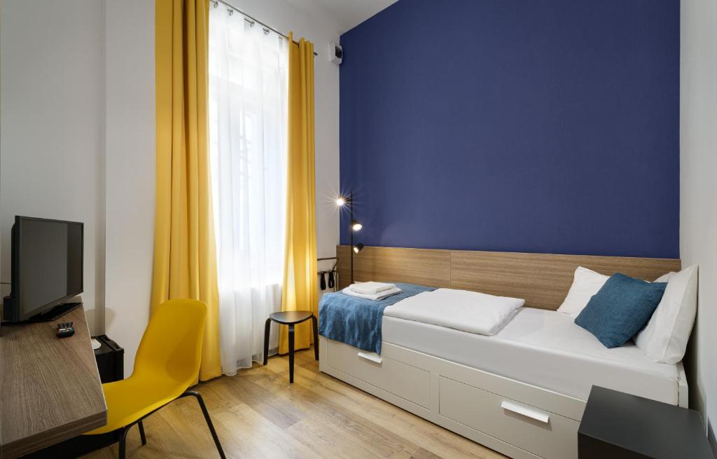 a bedroom with a bed and a blue wall at RES City Residence Hotel Budapest in Budapest