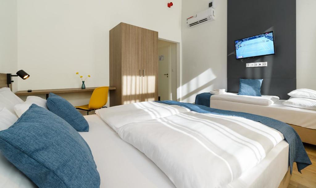 a hotel room with two beds and a tv at RES City Residence Hotel Budapest in Budapest