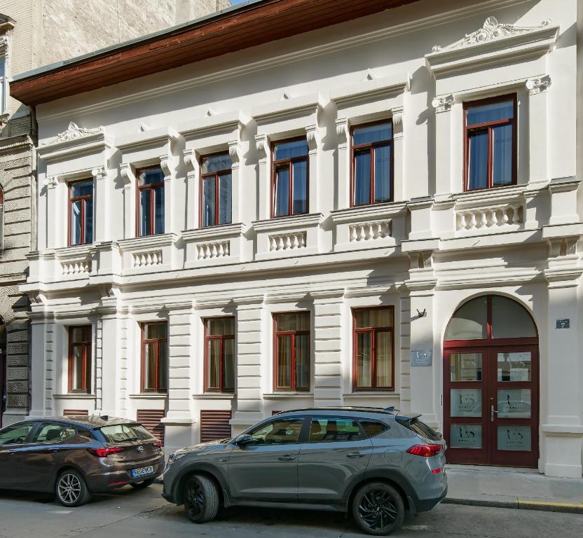 two cars parked in front of a white building at RES City Residence Hotel Budapest in Budapest
