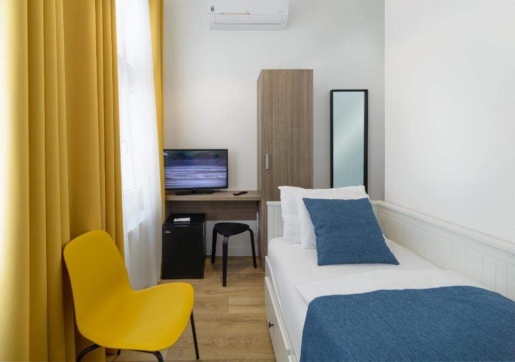 a hotel room with a bed and a yellow chair at RES City Residence Hotel Budapest in Budapest