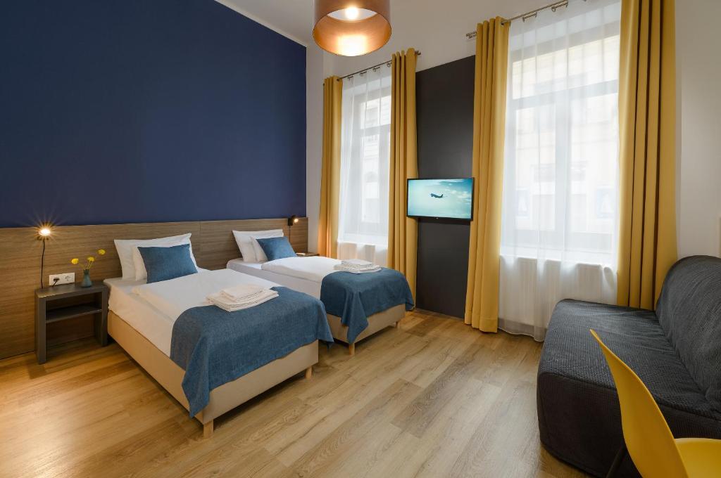 a hotel room with two beds and a couch at RES City Residence Hotel Budapest in Budapest