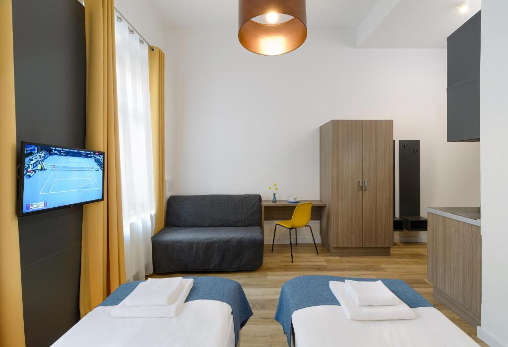 a room with two beds and a tv and a chair at RES City Residence Hotel Budapest in Budapest