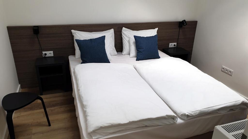 a bedroom with a large white bed with blue pillows at RES City Residence Hotel Budapest in Budapest