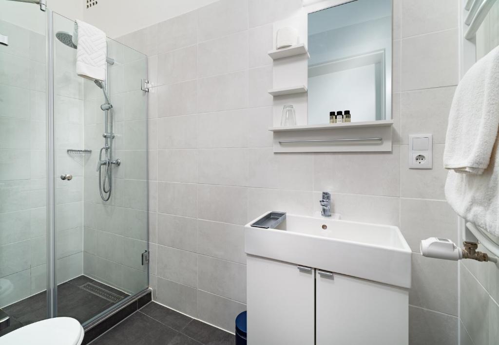 a white bathroom with a sink and a shower at RES City Residence Hotel Budapest in Budapest