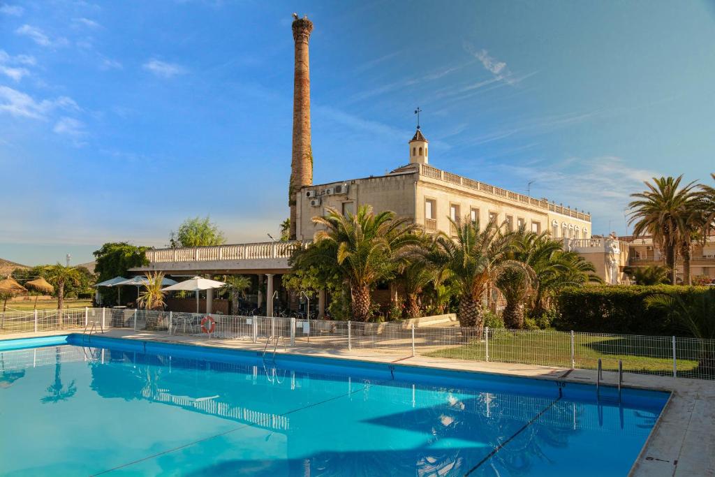 una gran piscina frente a un edificio con una palmera en Hotel Las Navas, en Malagón