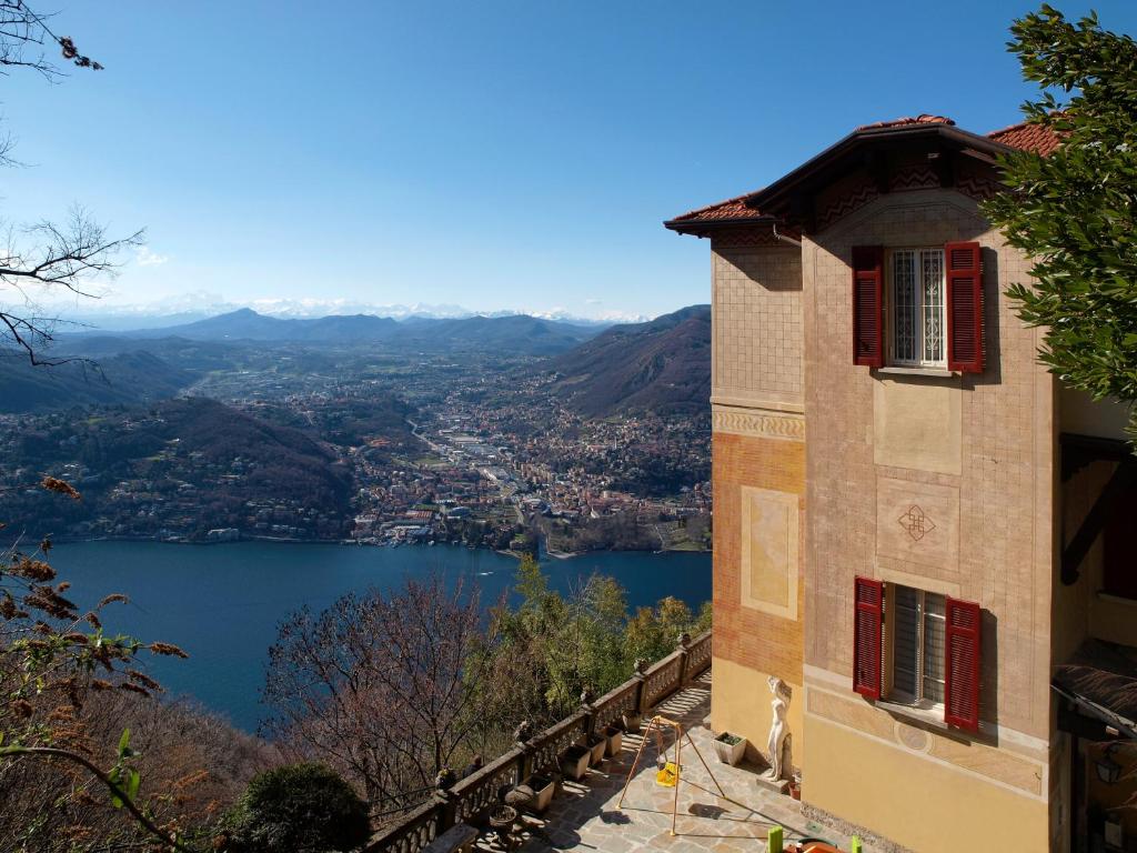 a building with red windows and a view of a lake at B&B Il Balcone sul Lago in Brunate