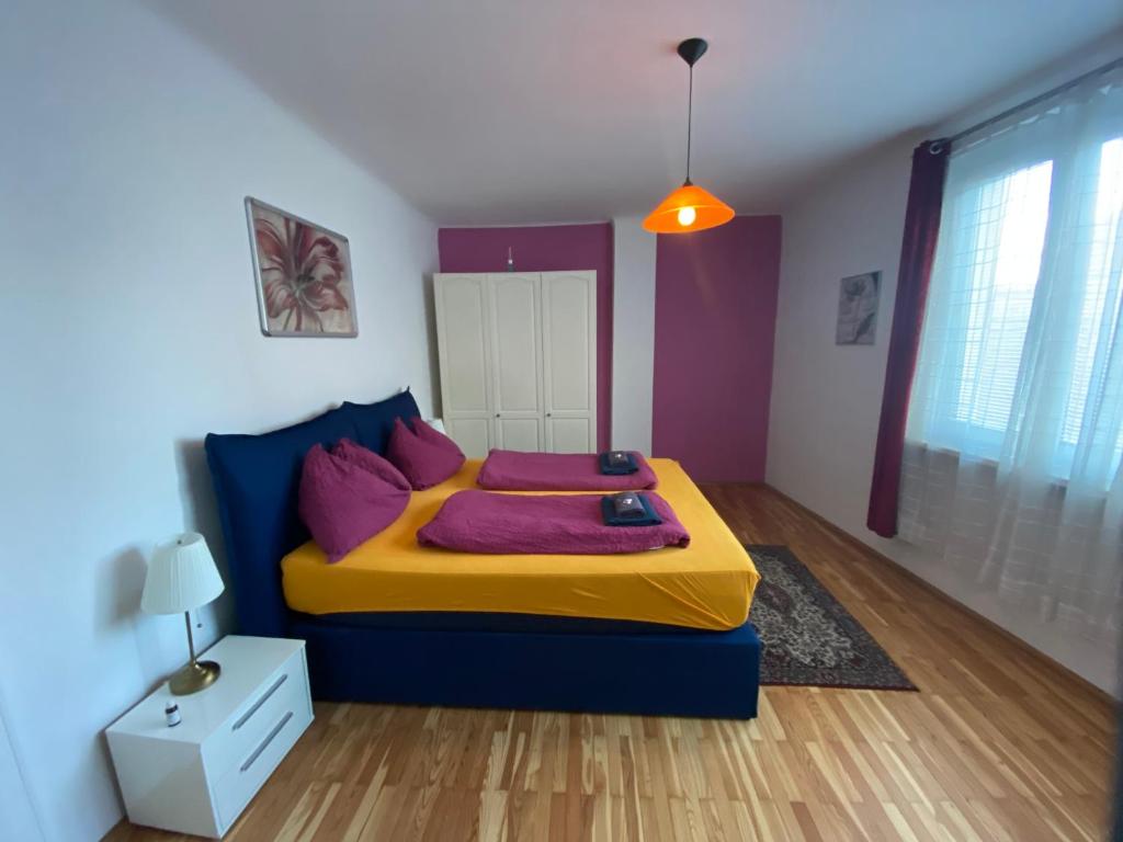 een slaapkamer met een blauw en geel bed met paarse kussens bij Apartment Domino in Wenen