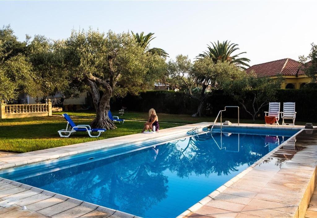 a girl is sitting next to a swimming pool at Villa with great pool dog friendly in Vinarós