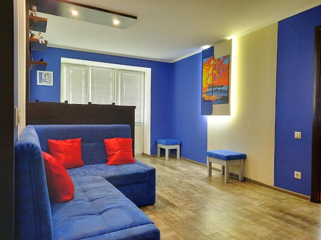 ポルタヴァにあるSea Style - Сеть апартаментов Alex Apartments Бесконтактное заселение 24-7の青いリビングルーム(青いソファ、赤い枕付)