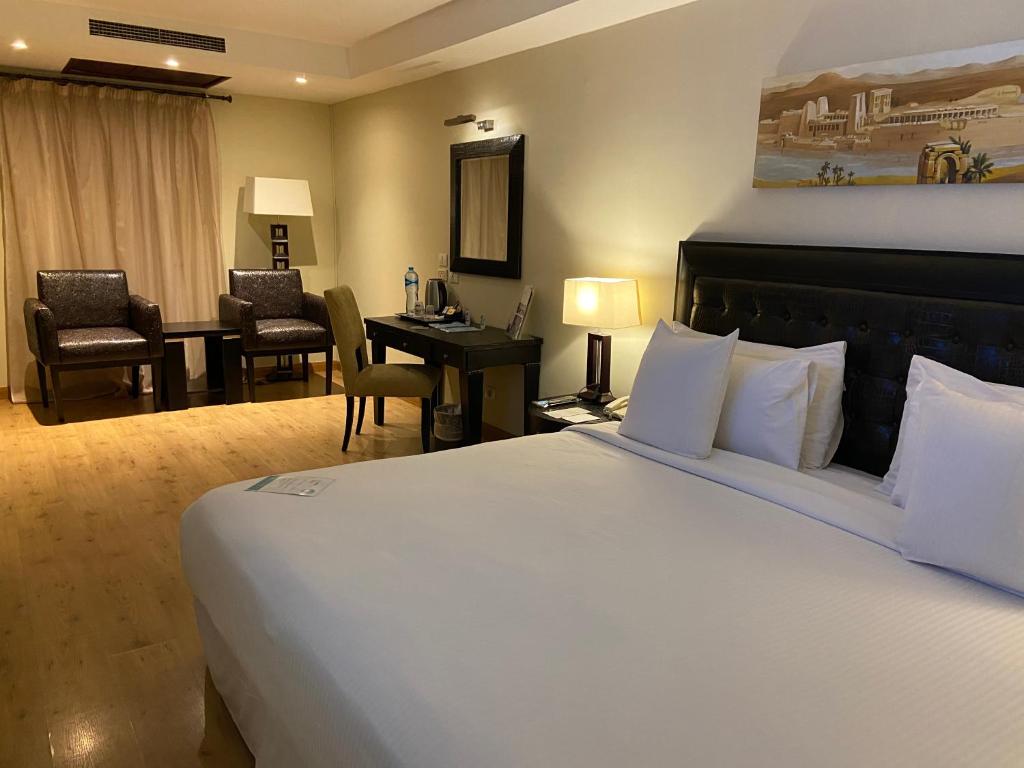 a hotel room with a large bed and a desk at Barceló Cairo Pyramids in Cairo