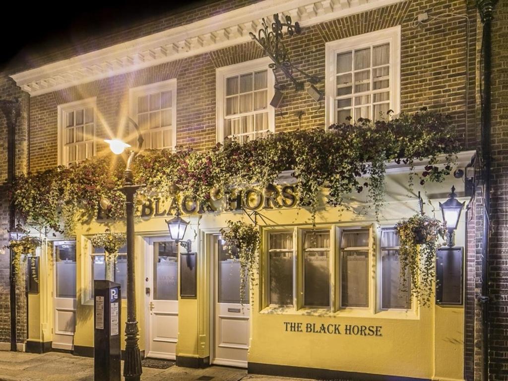 un bâtiment jaune avec un panneau indiquant le cheval noir dans l'établissement The Black Horse Inn, à Canterbury