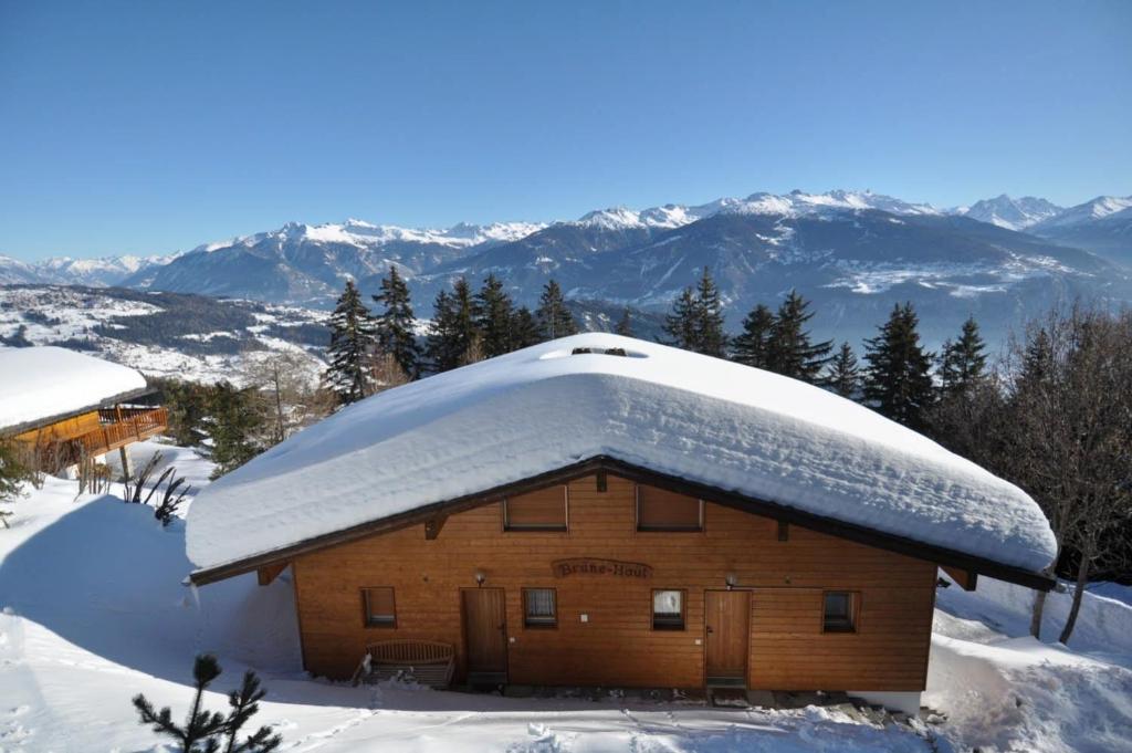 un edificio ricoperto di neve con montagne sullo sfondo di Chalet Brune-Haute ad Anzère