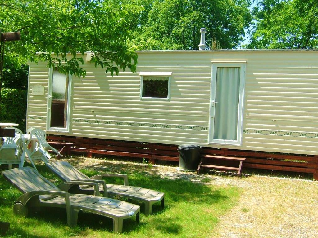 a cabin with benches in the grass in front of it at Charmant bungalow à Saint-Pierre-d'Oléron - Jardin privé in Saint-Pierre-dʼOléron