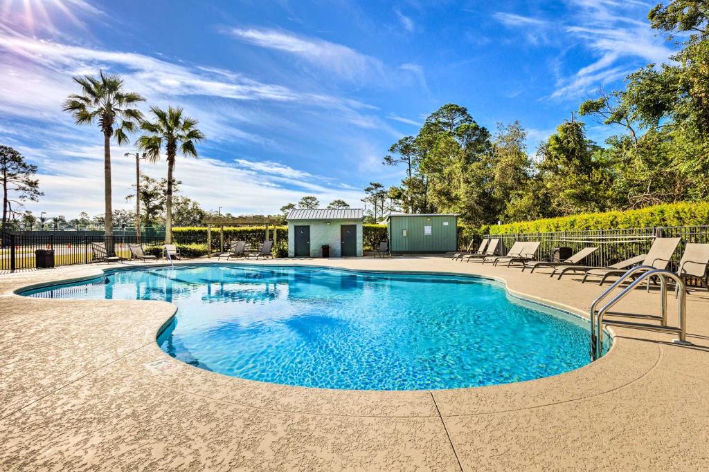 a swimming pool with chairs and trees in the background at Orange Beach Condo Private Boat Dock and Ramp in Orange Beach