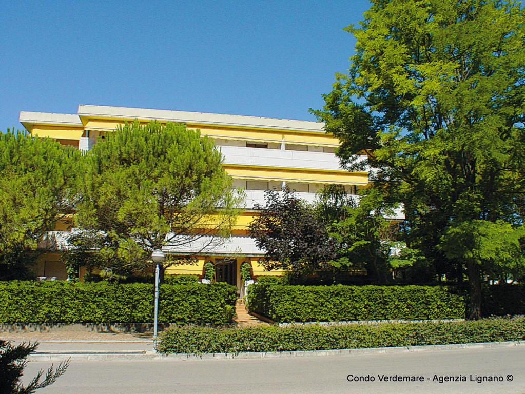 un gran edificio amarillo con árboles delante de él en Lignano, en Lignano Sabbiadoro