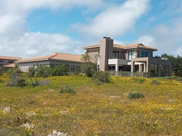 a house sitting on top of a field of flowers at Langebaan Golf Estate - Signature Hole 24hrs power in Langebaan