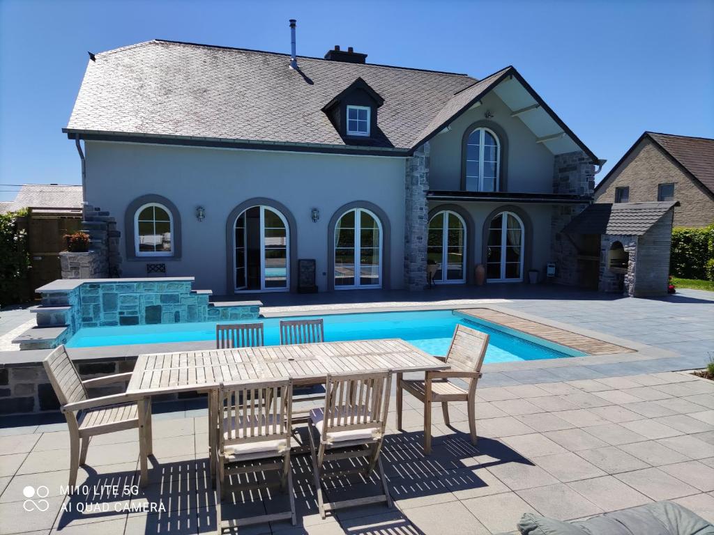 a patio with a table and chairs next to a pool at La Gerarie in Bastogne