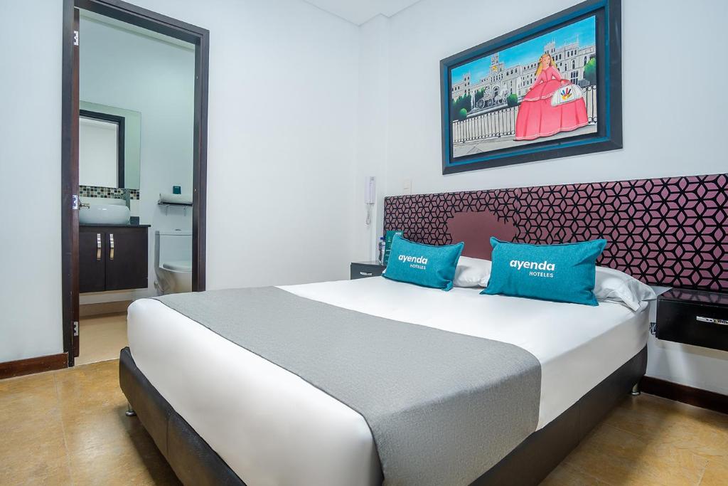 1 dormitorio con 1 cama blanca grande con almohadas azules en Ayenda La Tua Casa, en Bogotá