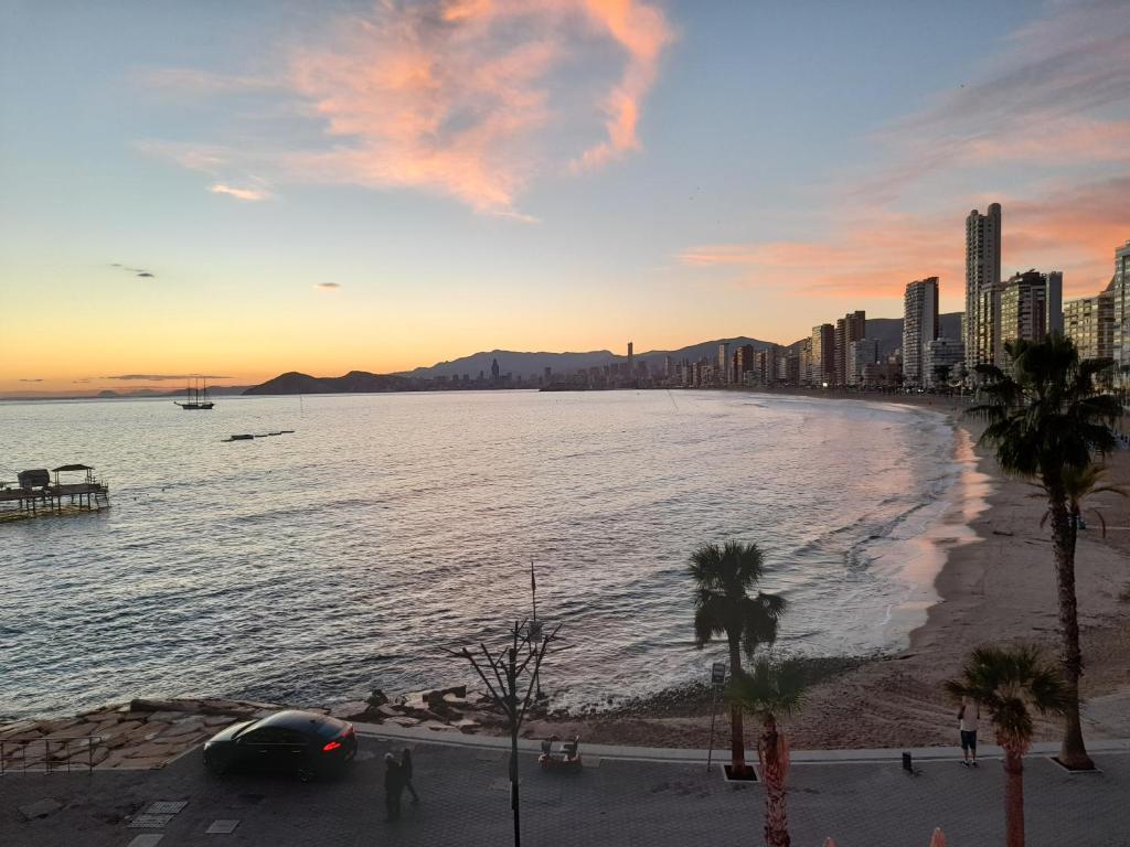 widok na plażę o zachodzie słońca z miastem w obiekcie Don Miguel 1-Fincas Benidorm w mieście Benidorm