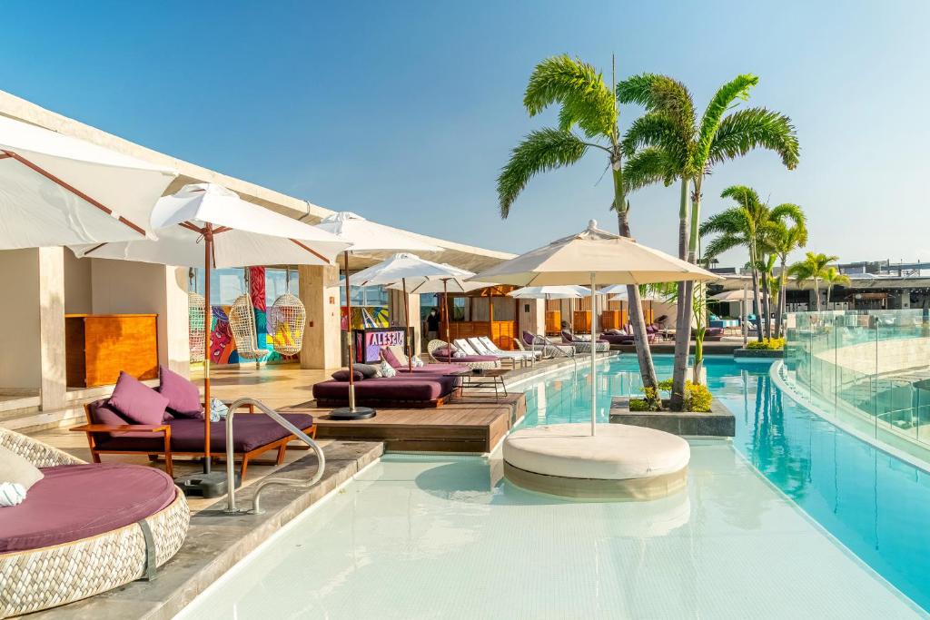 a swimming pool with lounge chairs and umbrellas at Hyatt Centric Playa del Carmen - Downtown House & Beach House in Playa del Carmen