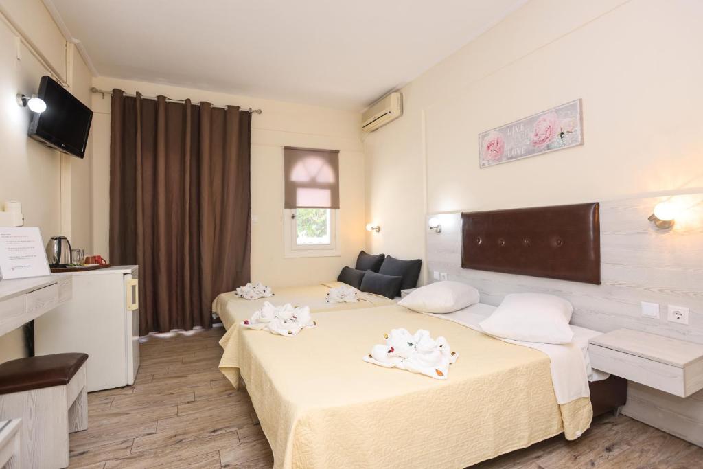 a hotel room with two beds and a television at Summer Beach Hotel in Polychrono