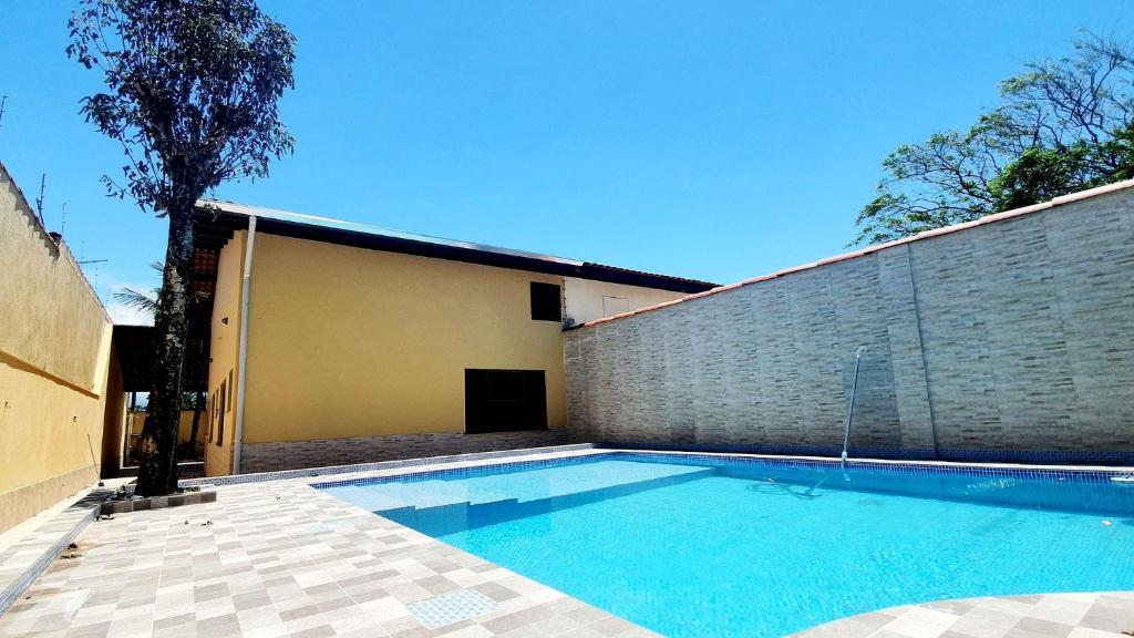 een zwembad voor een bakstenen muur bij Piscina, Churrasqueira, Bilhar, SmartTV, Wi-Fi, 400mts mar! in Itanhaém