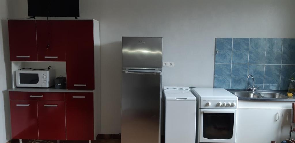 una pequeña cocina con estufa blanca y armarios rojos en John & Ghislaine en Donjeux