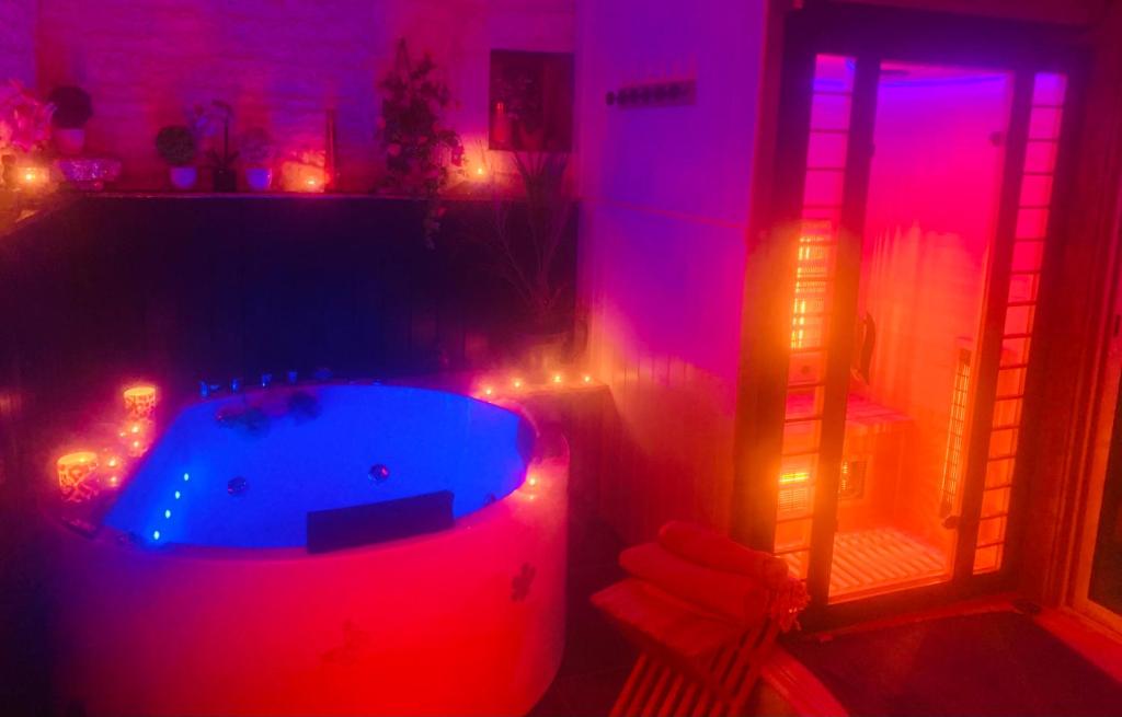 d'une baignoire dans une chambre avec des lumières rouges et violettes. dans l'établissement La Romance jacuzzi sauna jardin au calme, à Niort