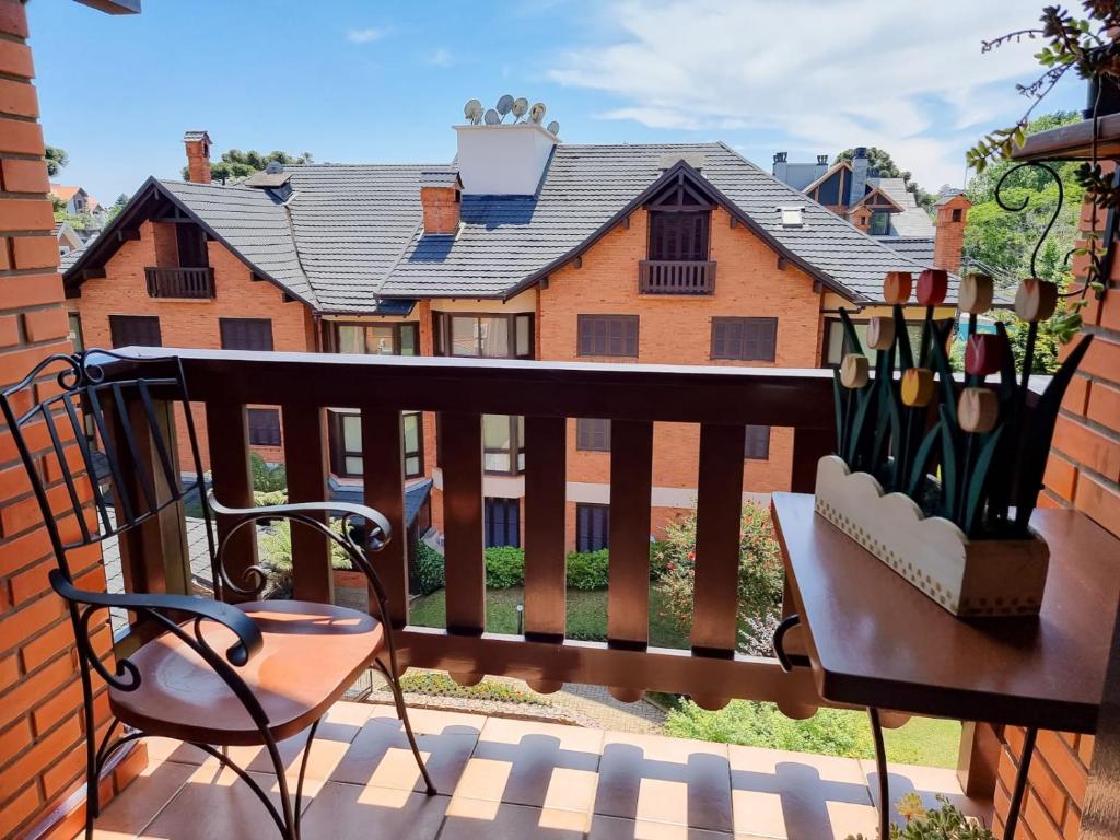 ein Balkon mit einem Stuhl und einem Haus in der Unterkunft Duplex aconchegante no Buganvilias Flat in Gramado