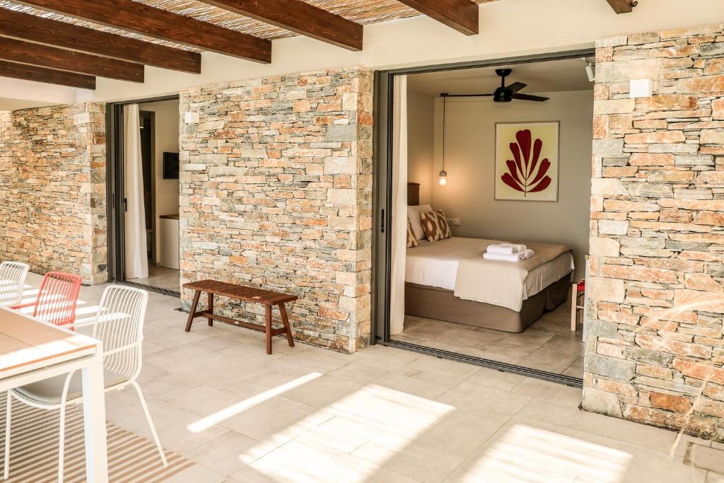une terrasse avec un lit et une chambre avec un mur en briques dans l'établissement Skiathos Symbol Villas, à Achladies