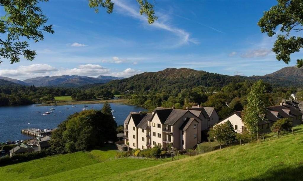 a house on a hill next to a body of water at Brand New - Contemporary - 2 Bedroom - 2 Bathroom - Spacious Apartment - Lake Views in Ambleside