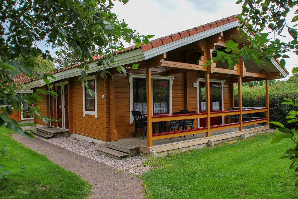 ein Holzhaus mit einer Veranda und einer Liegewiese in der Unterkunft Just Relax in Gramsbergen
