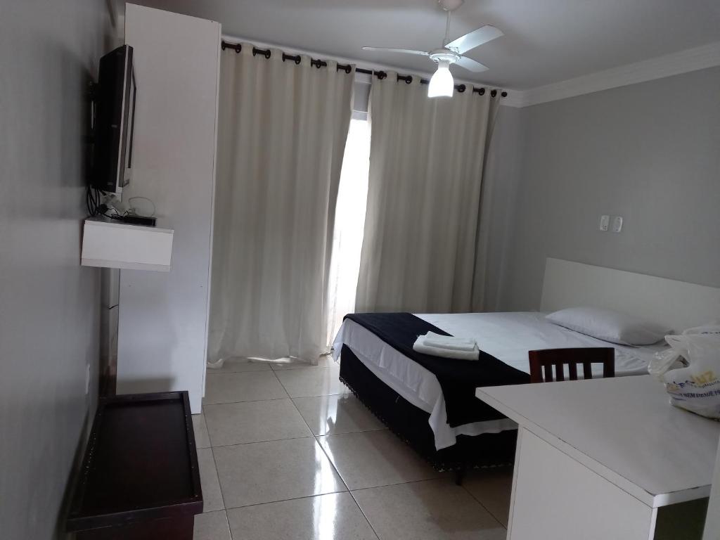 a bedroom with a bed and a television in a room at Uba Apart imóveis in Ubá