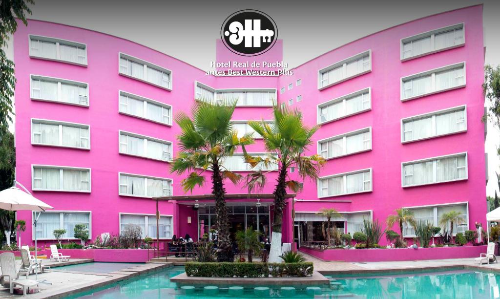 een roze gebouw met een zwembad ervoor bij Hotel Real de Puebla in Puebla